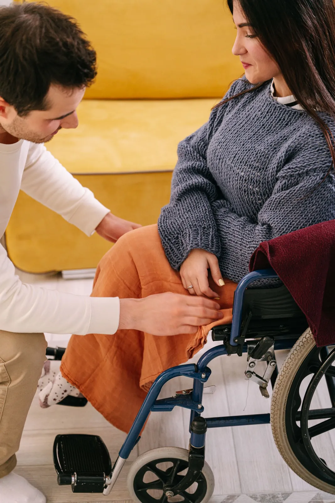 A support worker walks beside a woman using a wheelchair at home