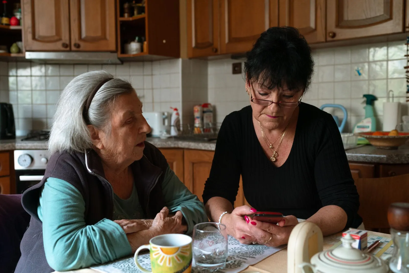 An older woman and her carer share a warm moment in her kitchen at home