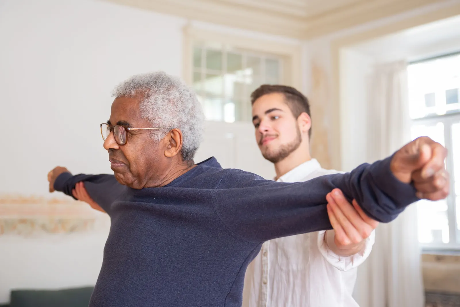 A man does guided stretching exercises at home with a support worker