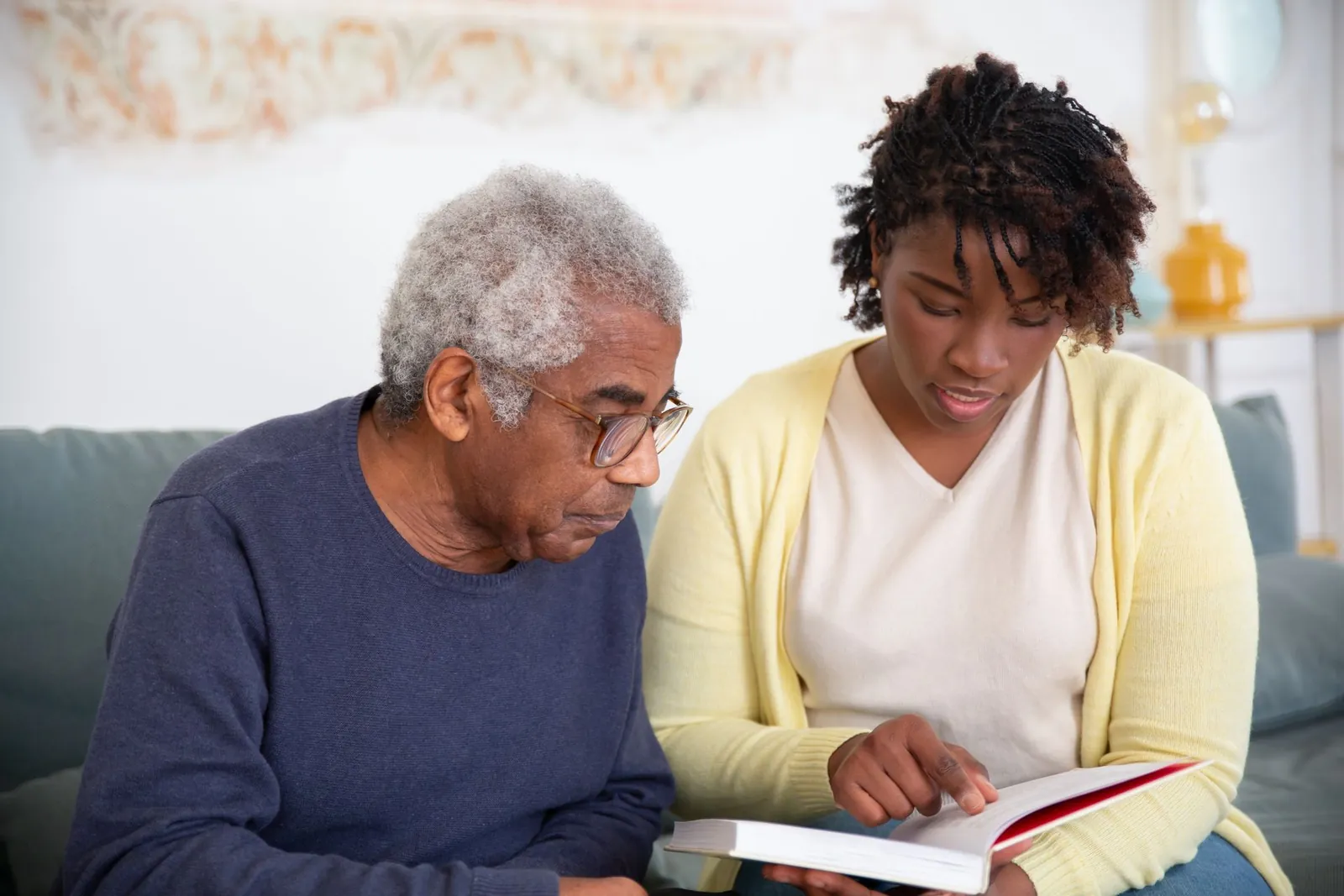 A support worker and an older man read together at home