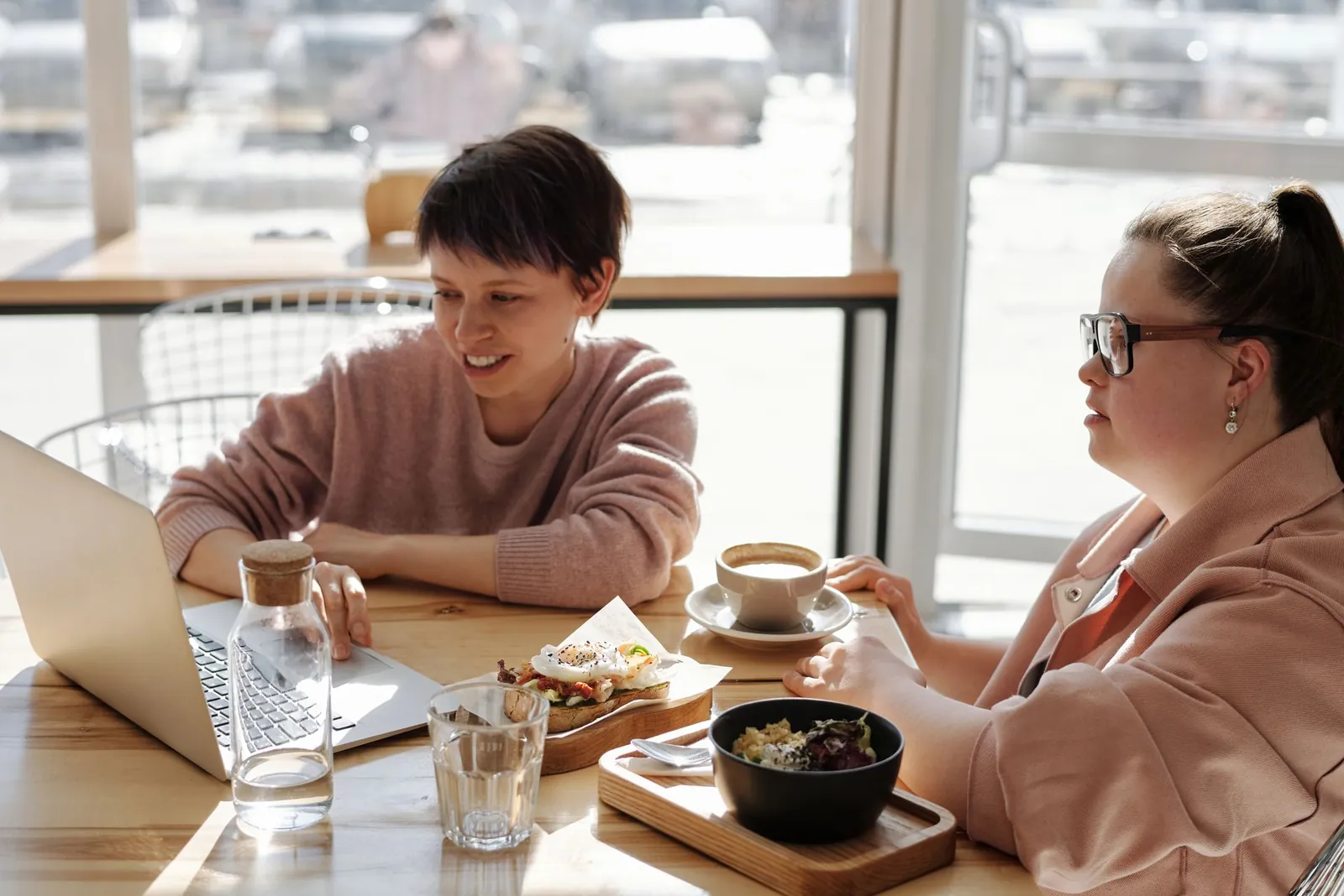 Two women go through the numbers together over coffee and a laptop