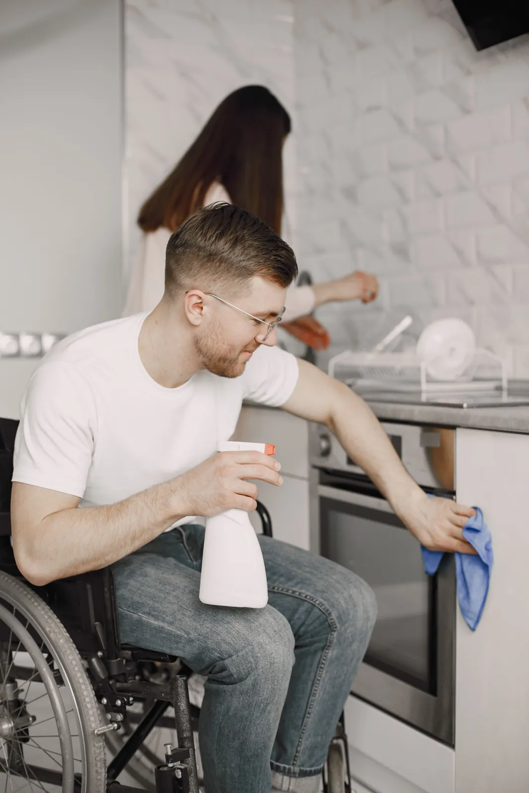 A man wipes down the bench of his own kitchen from his wheelchair